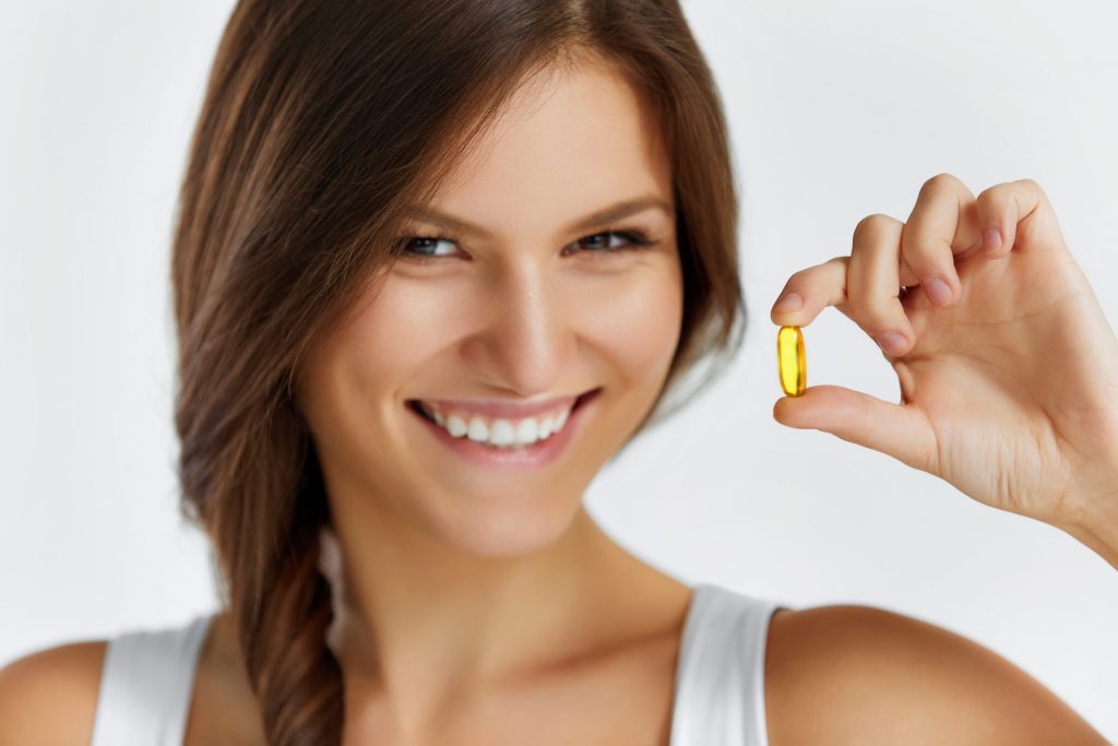 Nutrition. Healthy Lifestyle. Close Up Of Happy Woman Holding Pill With Cod Liver Oil Omega-3. Medicine, Nutritional Supplements. Sport, Beauty And Diet Concept. Vitamin D, E, A Fish Oil Capsules.